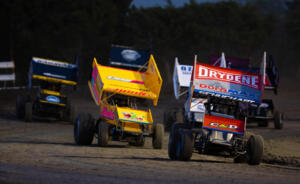 A pack of Sprint Cars race out of the turn at Devil's Bowl Speedway