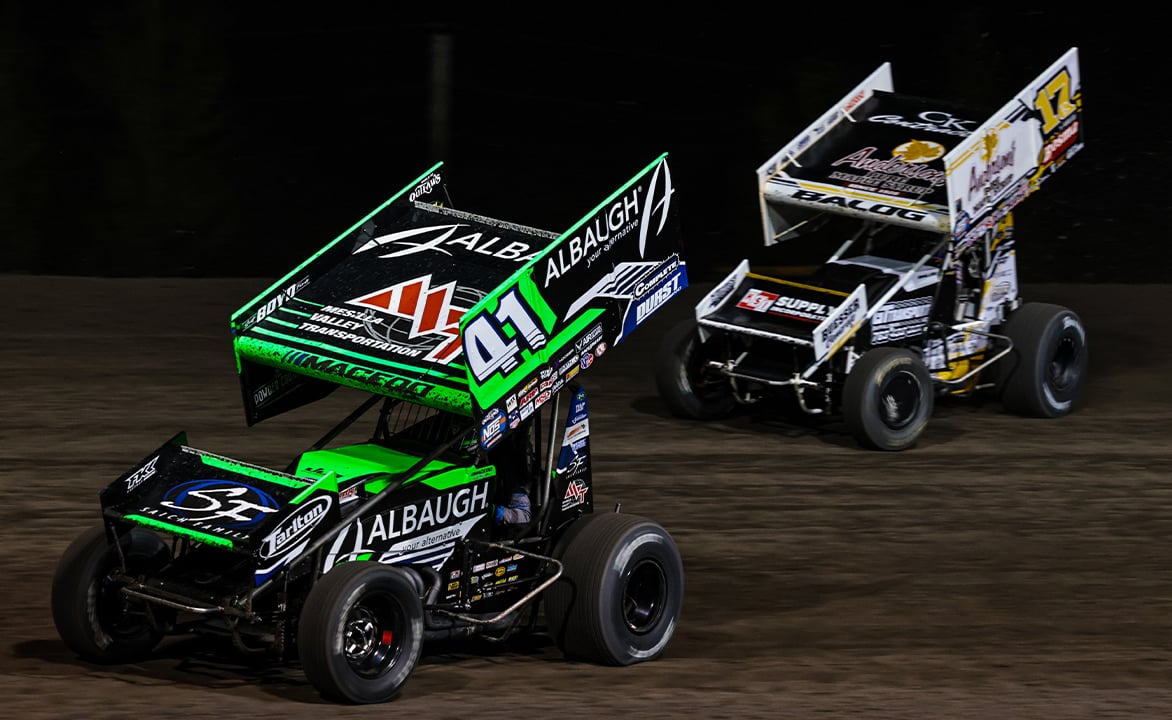 Carson Macedo drives by Bill Balog at Fix It Forward Speedway
